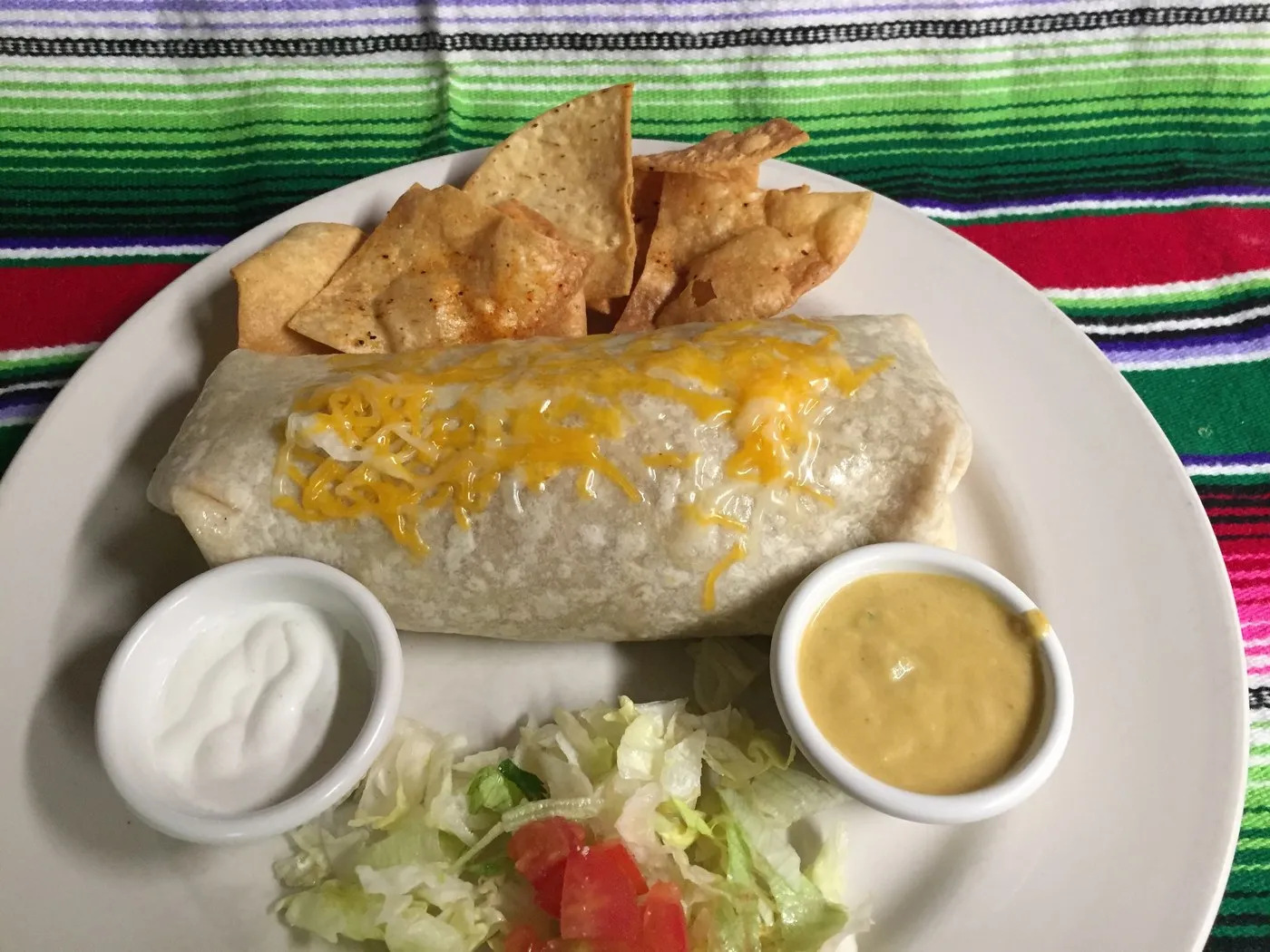 Burrito topped with cheese, with sour cream and salsa