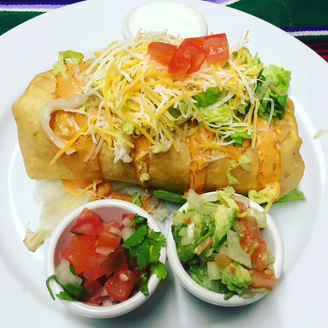 Chimichanga topped with lettuce, tomato and cheese