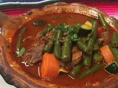 Caldo de res with beef, green beans, carrot and squash in a clay bowl