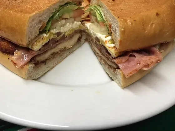 A torta on a toasted telera roll, cut in half, with ham and cheese